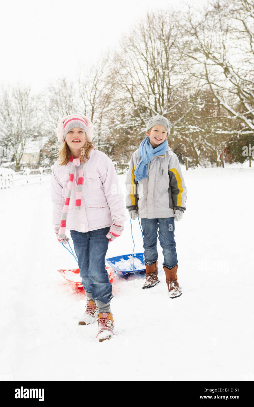 Kinder ziehen Schlitten durch tief verschneite Landschaft Stockfoto