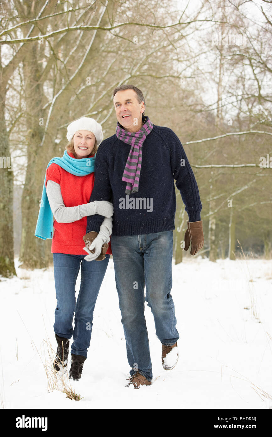 Älteres Paar zu Fuß durch den verschneiten Wald Stockfoto