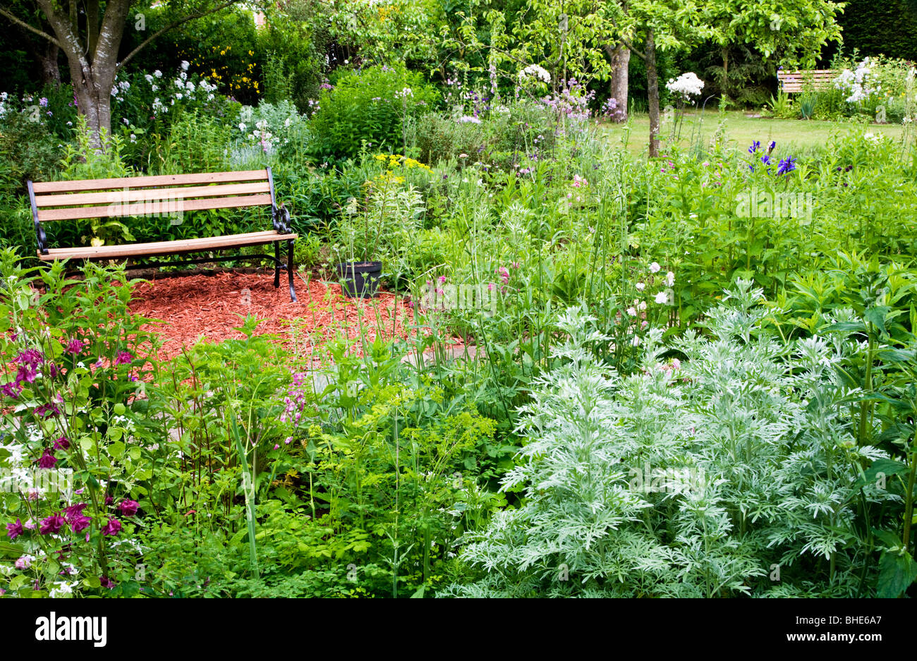 Ein Holzsitz oder Bank in einer ruhigen Ecke eines englischen Gartens. Stockfoto
