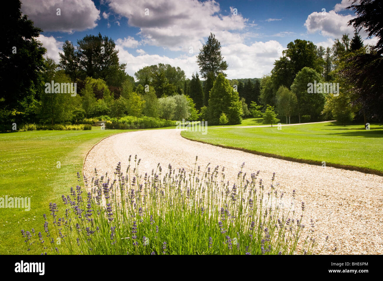 Einen geschwungenen Kiesweg durch einen englischen Landsitz an einem sonnigen Sommertag Stockfoto