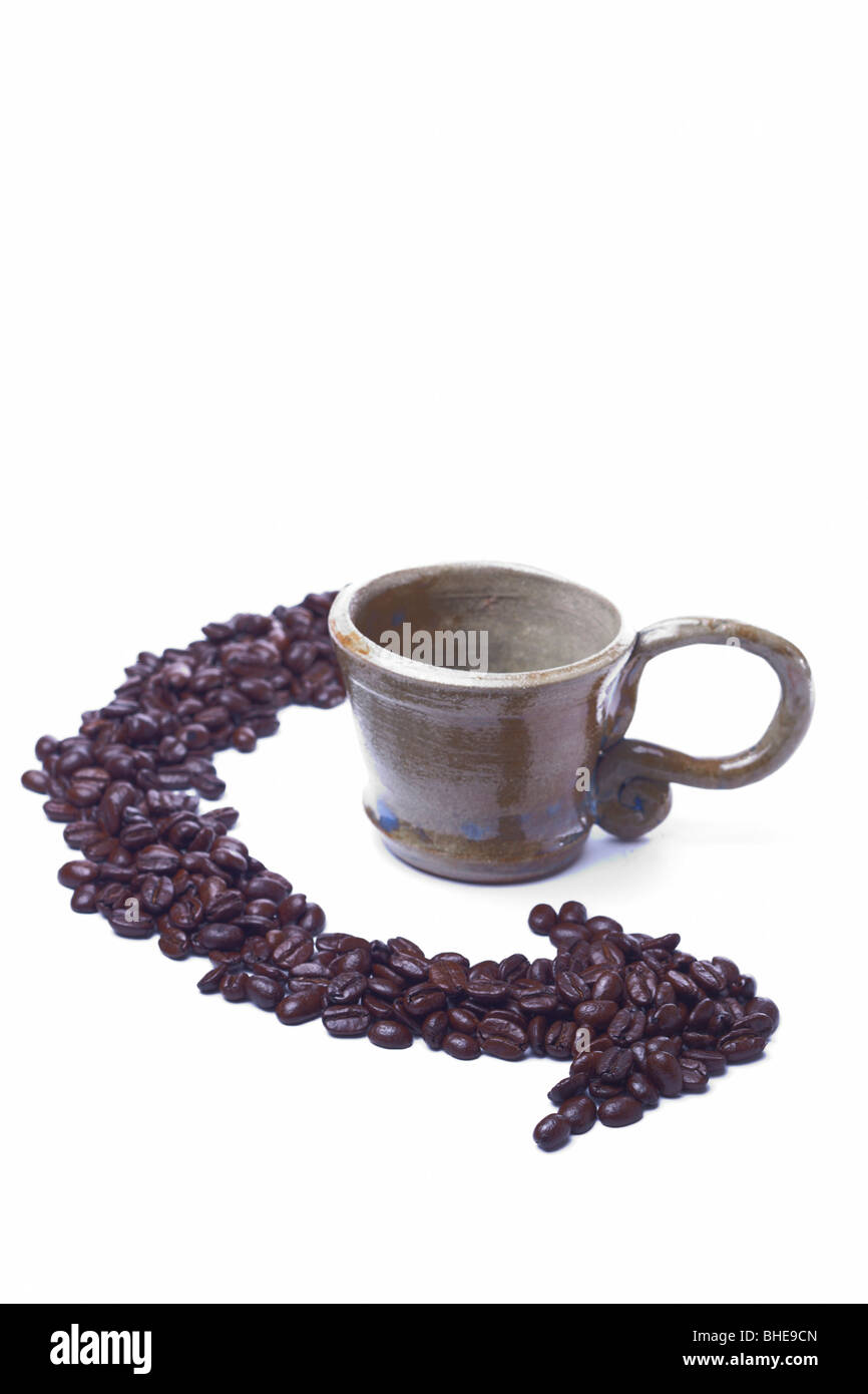 Eine Tasse sitzt auf einem weißen Hintergrund mit Kaffeebohnen in Pfeil-Form angeordnet Stockfoto