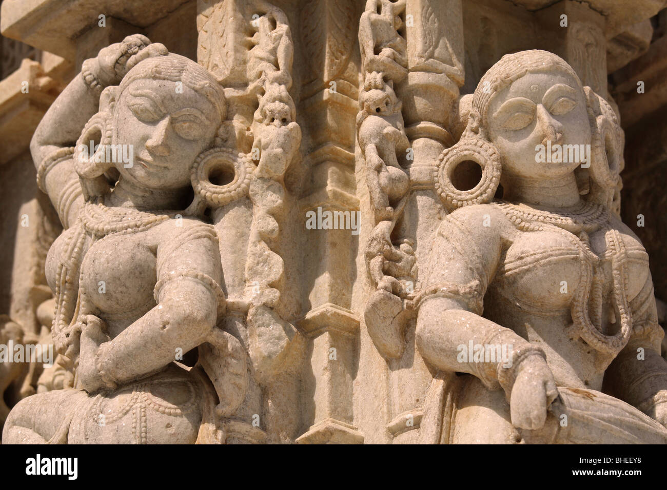 Weiße Stein Jain oder Hindu tanzenden Mädchen mit große Creolen, Ketten und anderen Schmuck - Skulpturen auf einem Jain-Tempel. Stockfoto