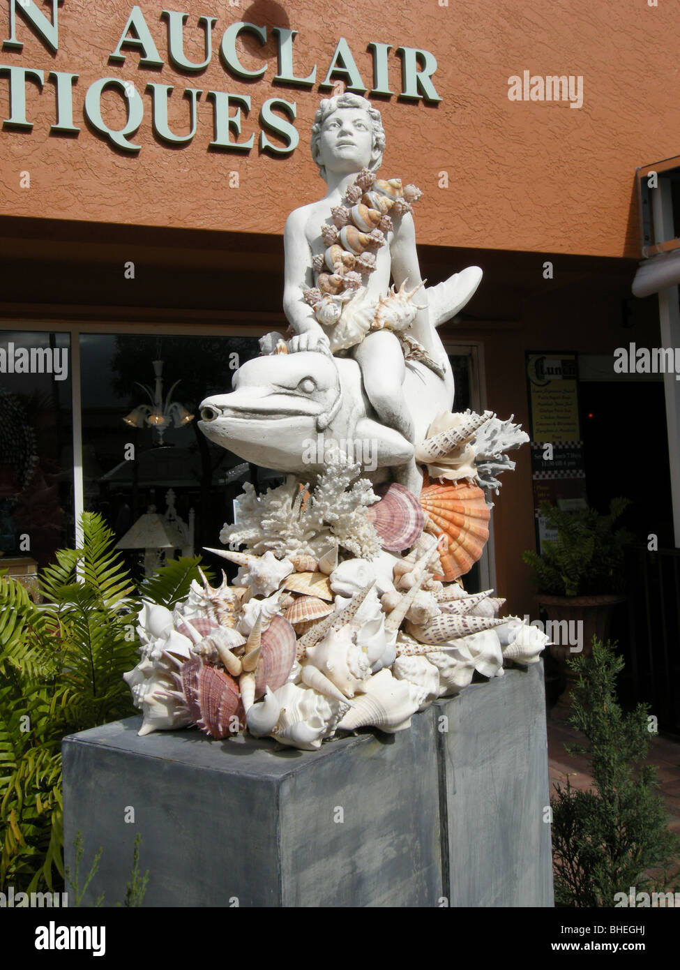 Junge auf einem Delphin Schale Skulptur außerhalb ein Antiquitätengeschäft auf Fifth Ave South Naples Florida USA Stockfoto