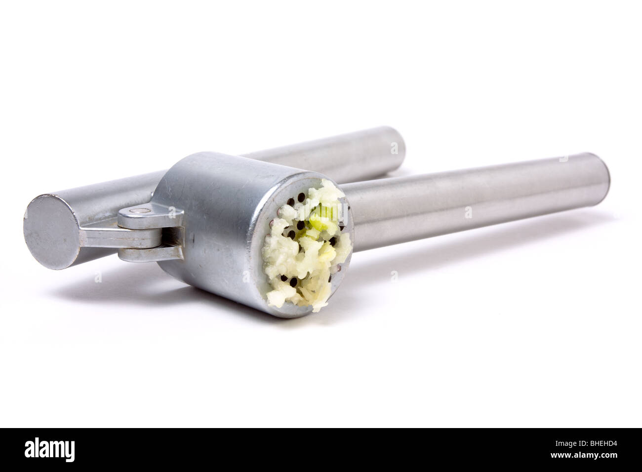 Zerdrückten Knoblauch Nässen aus glänzendem Silber Knoblauchpresse auf weißen Hintergrund isoliert. Stockfoto