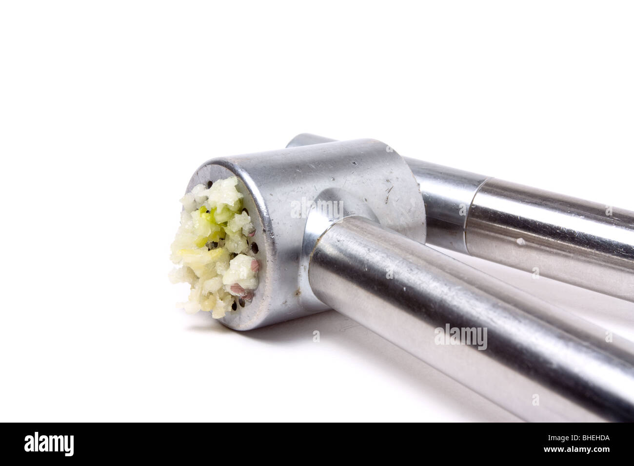 Zerdrückten Knoblauch Nässen aus glänzendem Silber Knoblauchpresse auf weißen Hintergrund isoliert. Stockfoto