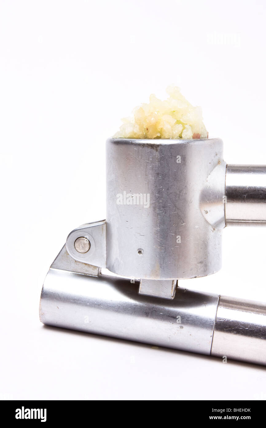 Zerdrückten Knoblauch Nässen aus glänzendem Silber Knoblauchpresse auf weißen Hintergrund isoliert. Stockfoto