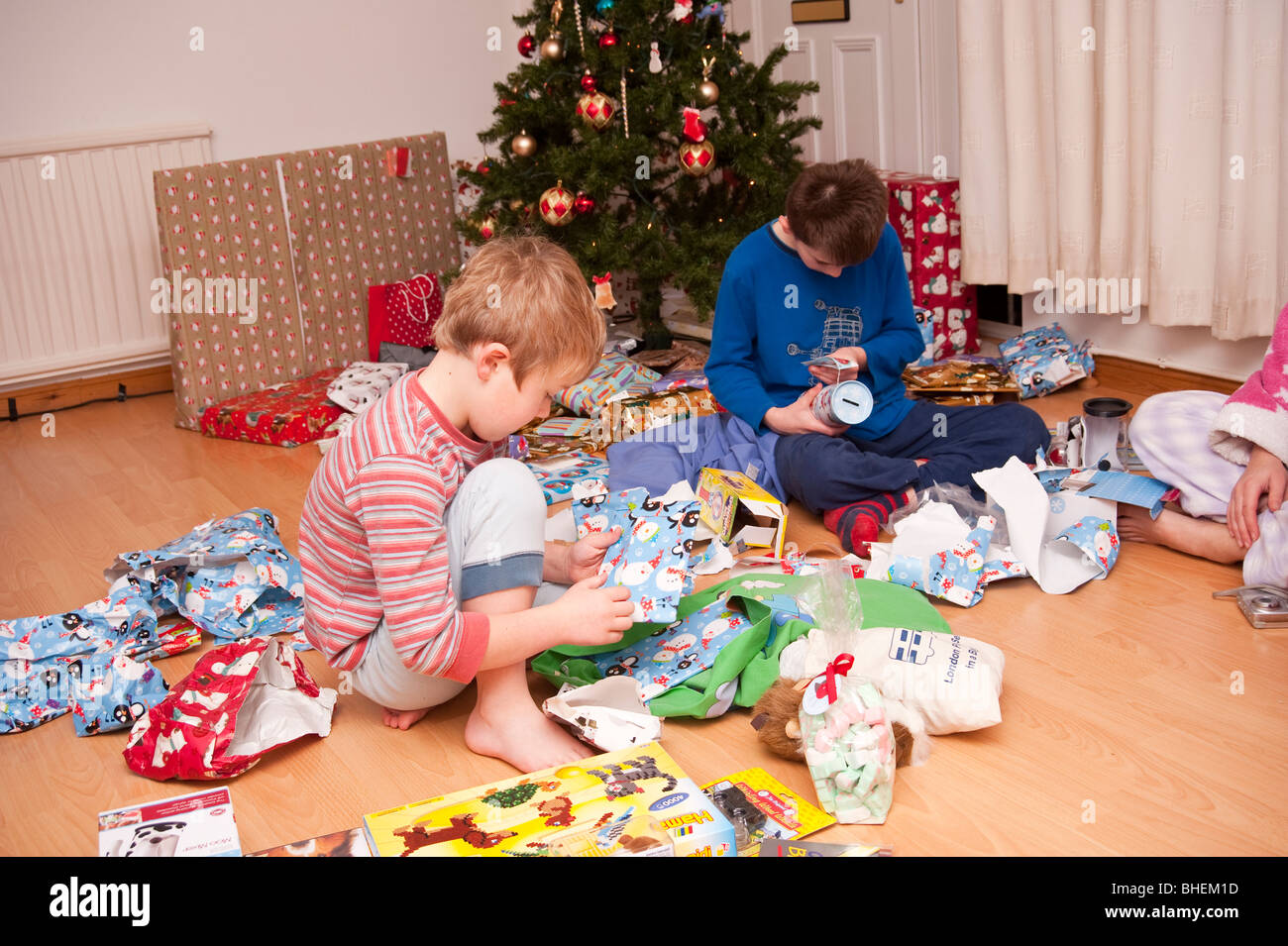 Ein MODEL Release Bild der beiden Brüder öffnen ihre Weihnachten präsentiert unter dem Baum im Vereinigten Königreich Stockfoto