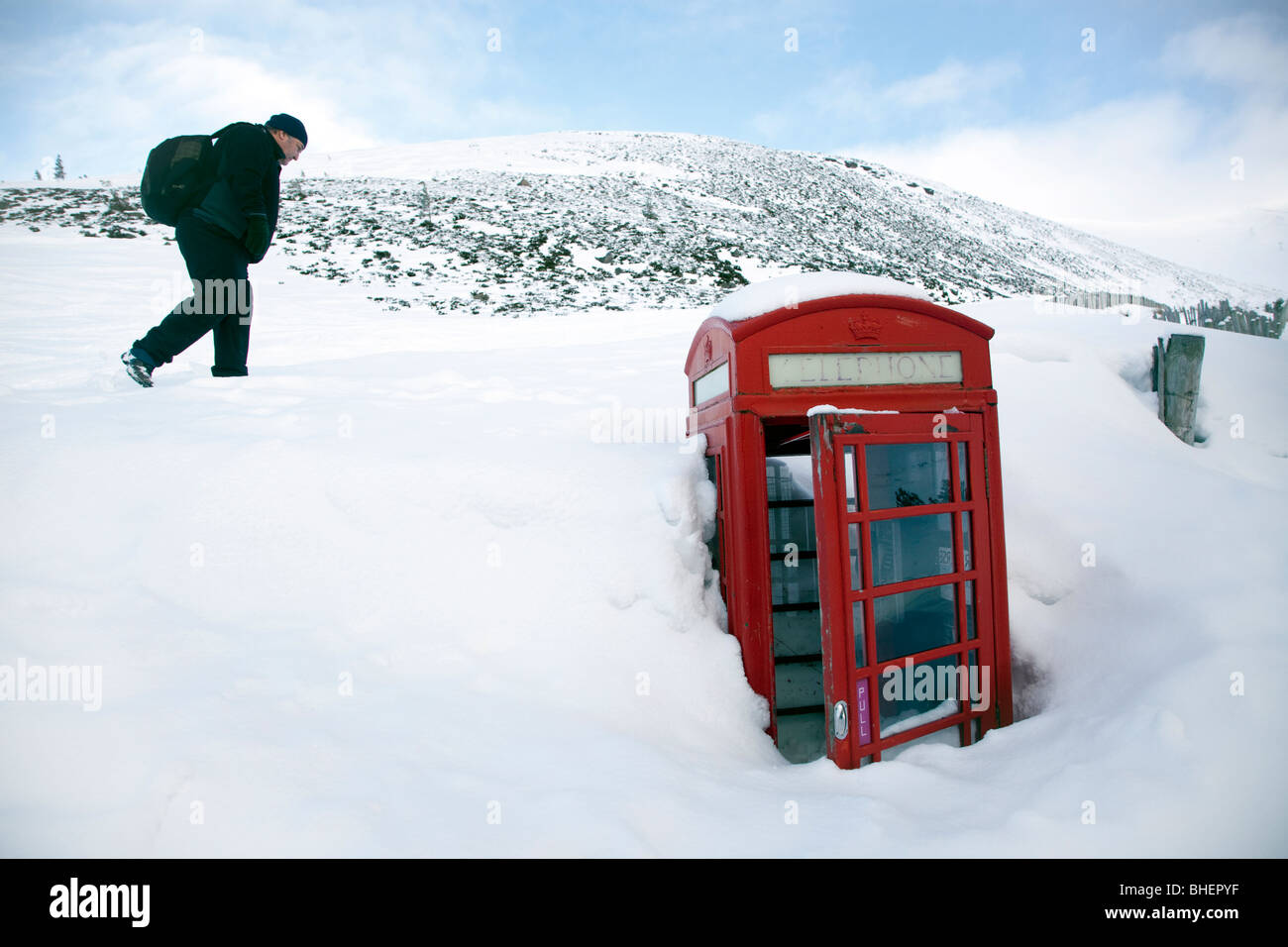 Tiefschnee vergräbt fast eine traditionelle rote Telefonzelle auf den Bergen in Aviemore, Cairgorms, Schottland. Stockfoto
