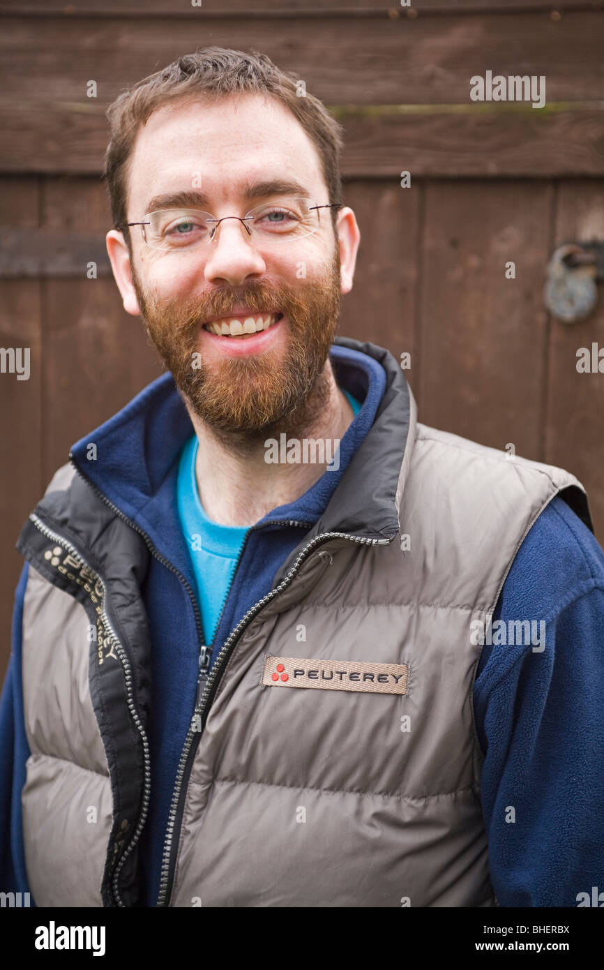 Ein bärtiger Mann lächelt vor einer Holzhütte. Stockfoto