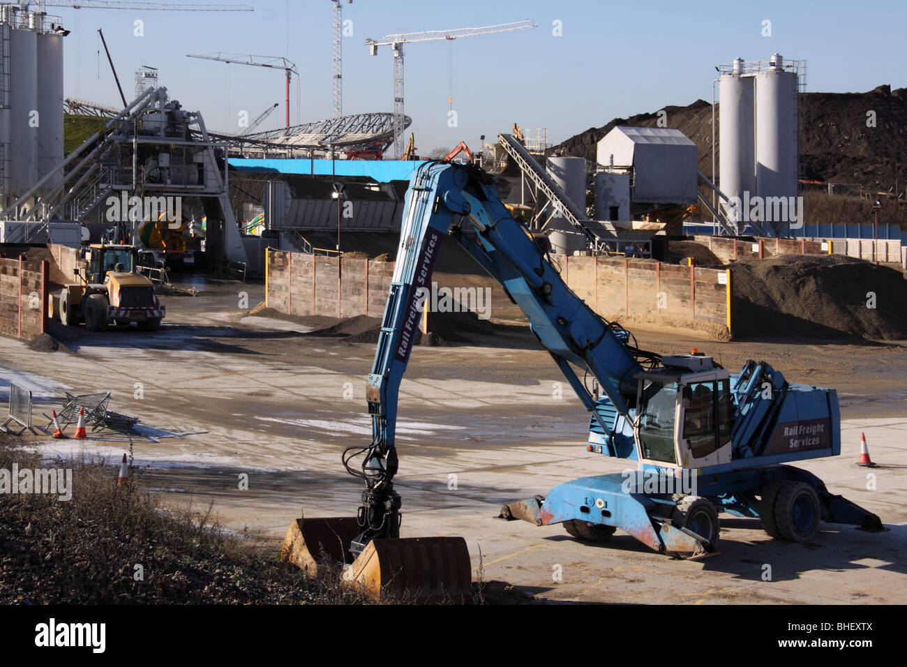 Bauen Sand und mechanische Digger im Vordergrund mit Stadion nur sichtbar im Hintergrund. Stockfoto