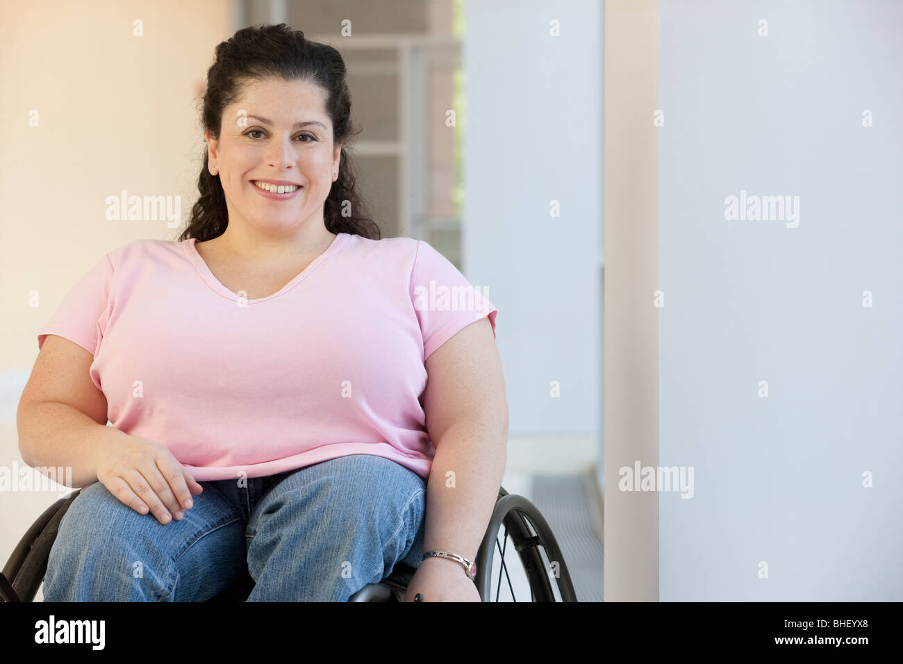 Behinderte Frau in einem Rollstuhl sitzt lächelnd Stockfoto