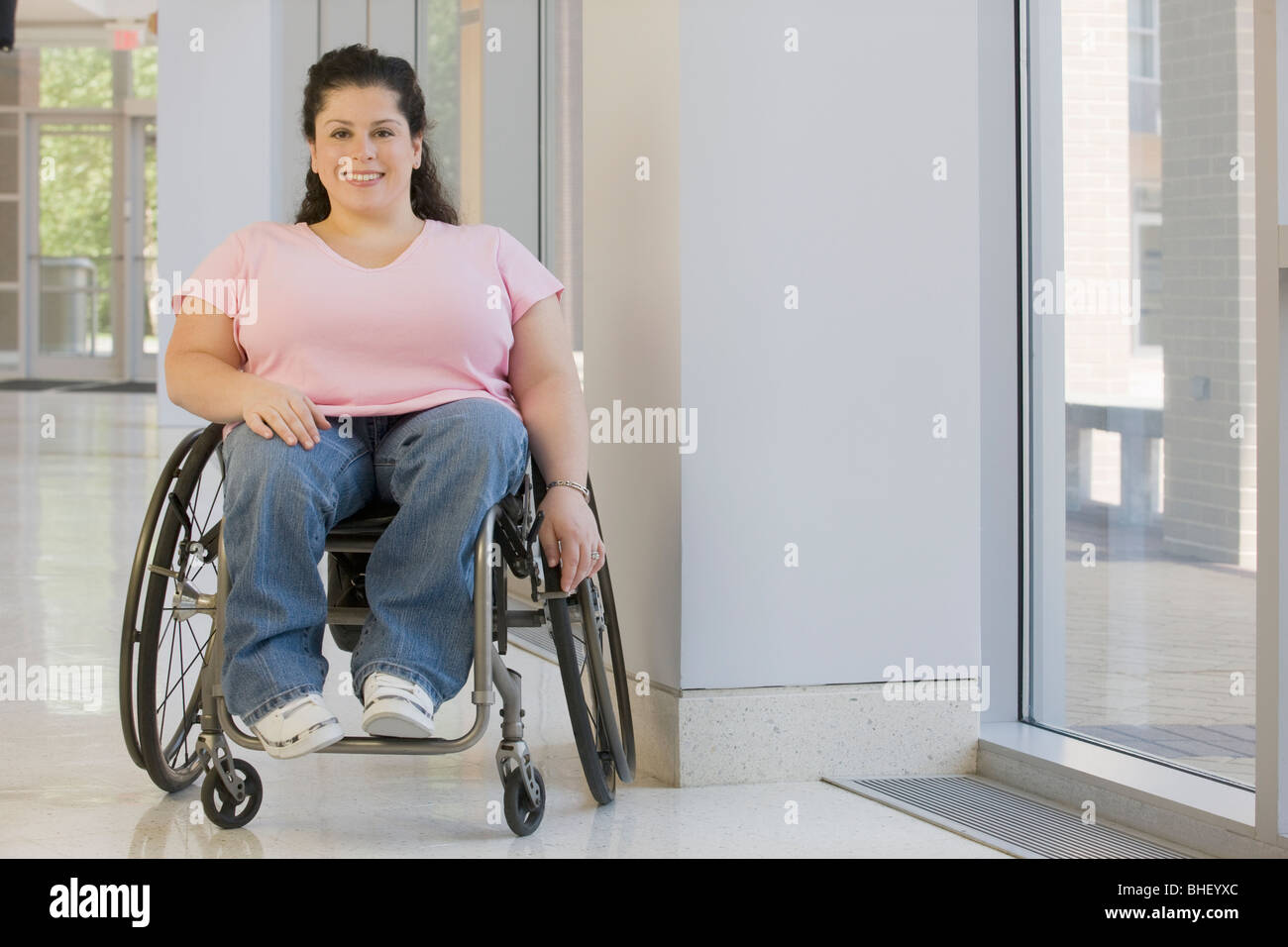 Behinderte Frau in einem Rollstuhl sitzt lächelnd Stockfoto