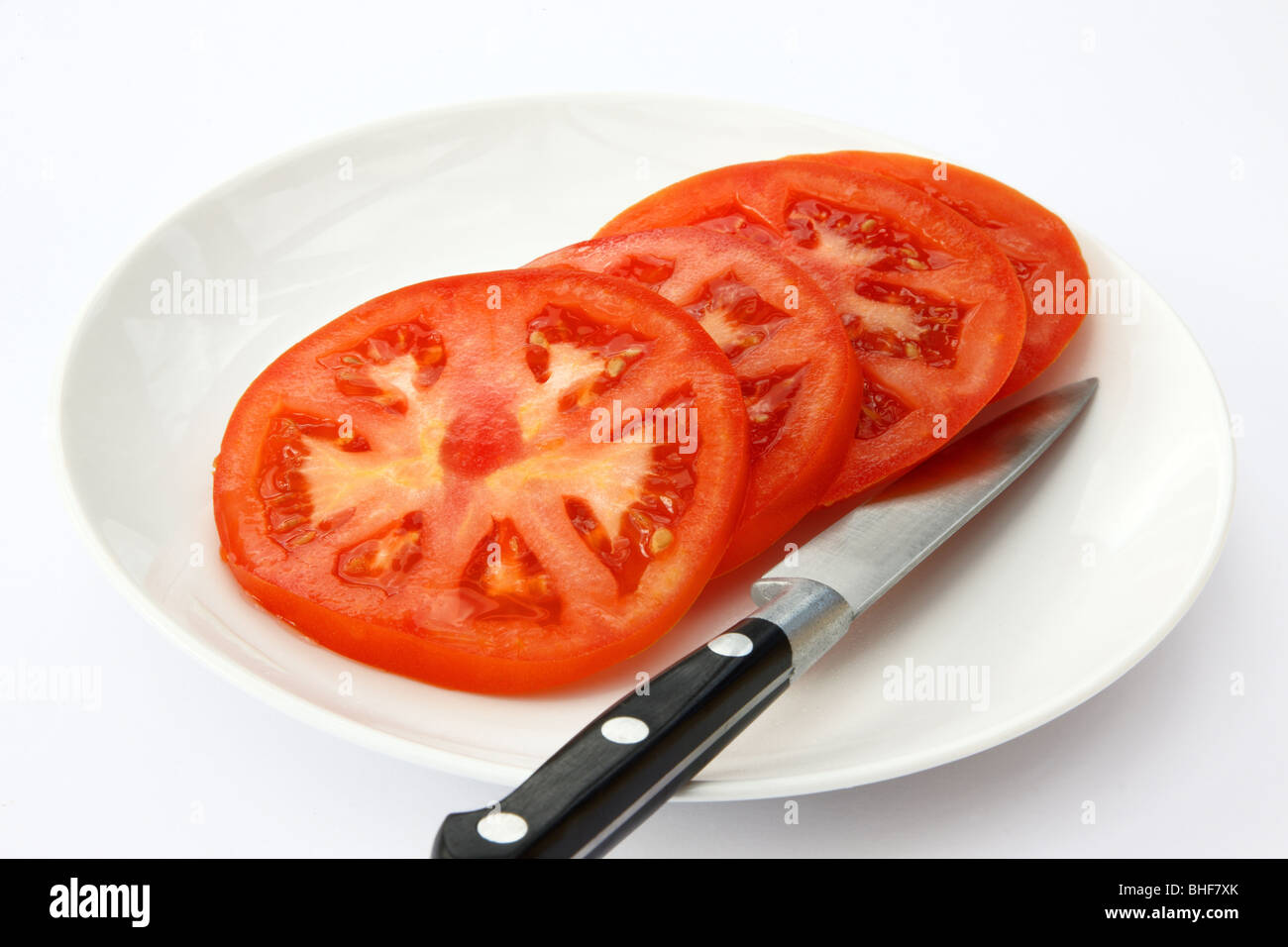 Große, Reife, saftige, rote Rindfleisch Tomaten auf einem weißen Teller mit Küchenmesser geschnitten. Stockfoto