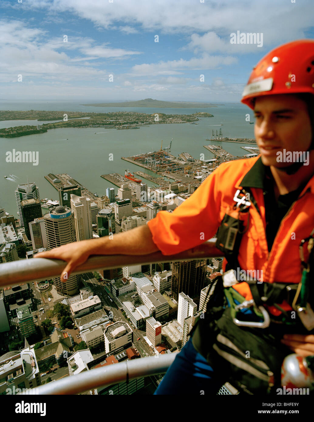 Junger Mann mit Kletterausrüstung auf Sky Tower, Blick auf Central Business District und Waitemata Harbour, Auckland, Norden Stockfoto