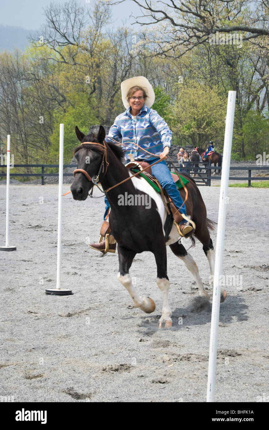 Glücklicher Fahrer, die Spaß am Malen Pferd durchläuft der Pole verbiegen Wettbewerb bei einem Show-Event. Stockfoto