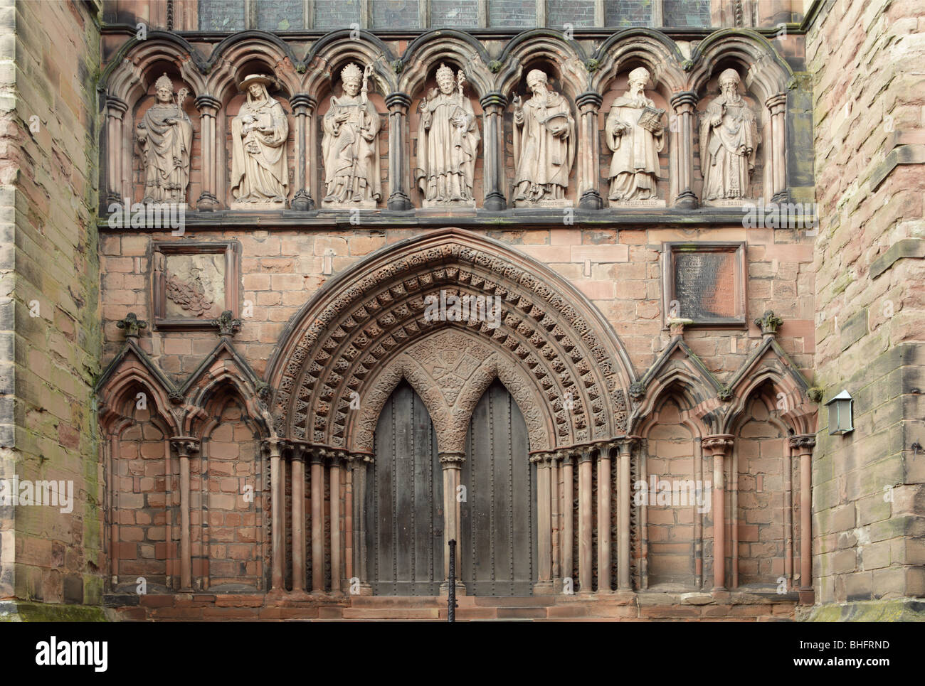 Erweiterte Ansicht der südlichen Tür bei Kathedrale von Lichfield, kunstvoll geschnitzte Stein schmückt die feinere Eichentür. Stockfoto