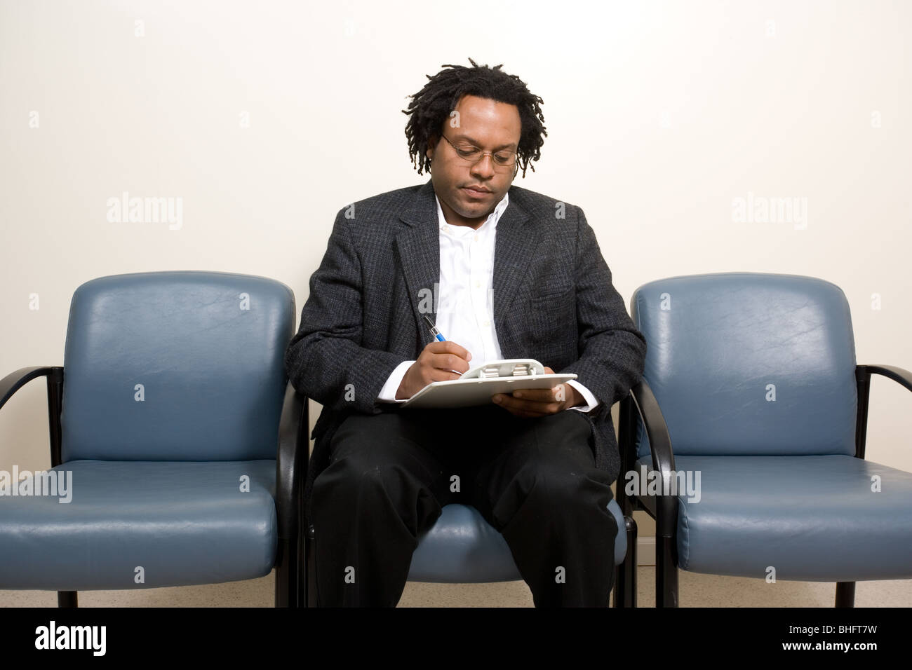 Schwarzer Mann Antworten Anamnese Fragebogen während des Wartens auf seinen Arzt oder Physiotherapeuten oder des Psychologen Termin Stockfoto