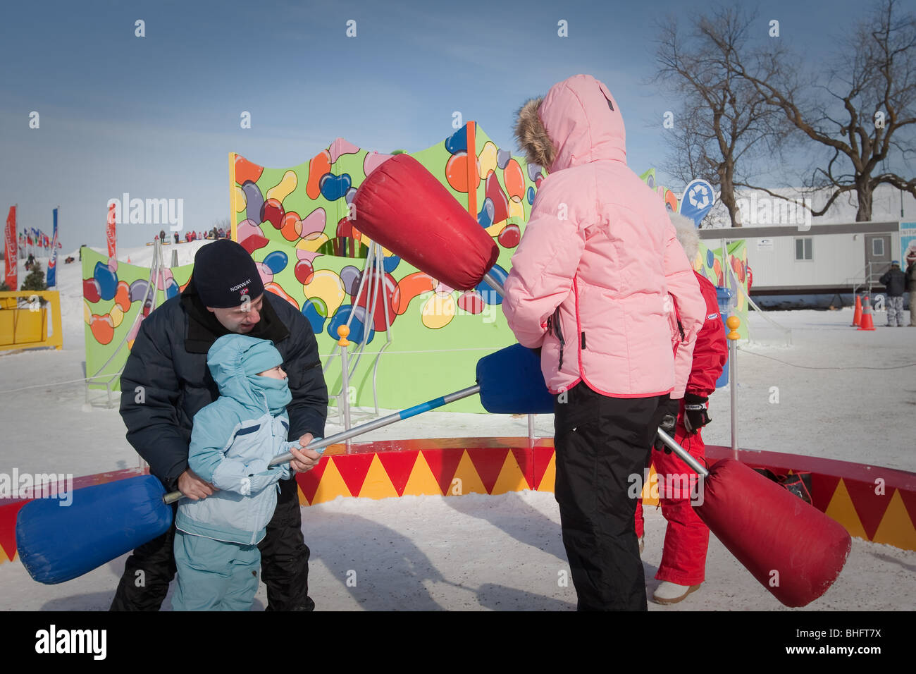 Ein Mann hilft seiner Tochter, wie sie spielt Ritterturniere mit ihrer Mutter in der Quebec-Winter-Karneval (Carnaval de Quebec) Stockfoto