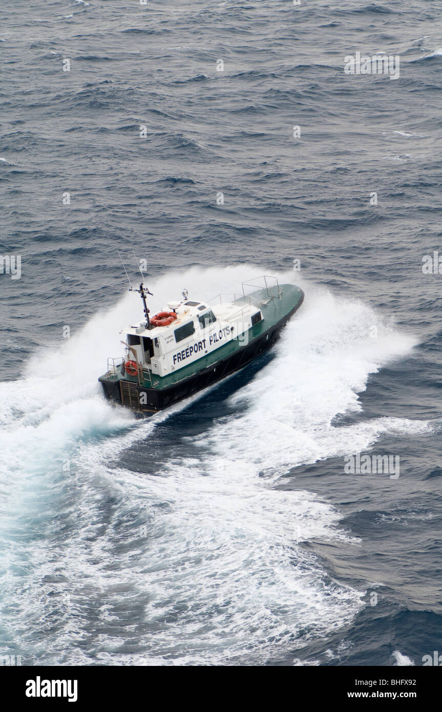 Ein Lotsenboot pflügt durch eine Welle in einer Bemühung, einen Port-Piloten zu einem anderen Ozean-Schiff in Freeport auf den Bahamas zu liefern. Stockfoto