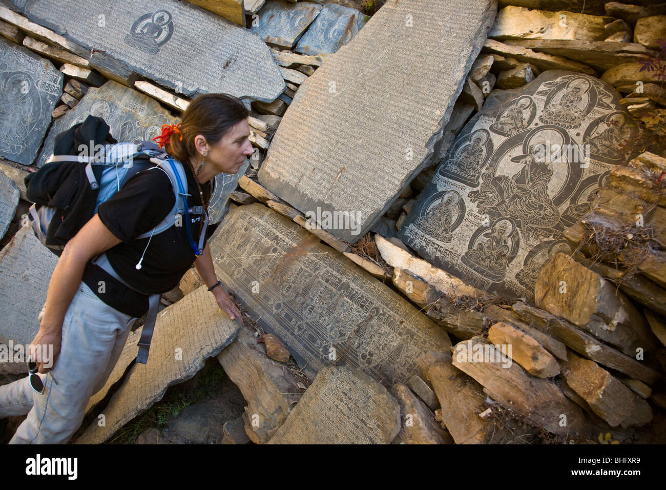 Christine Kolisch untersucht einen tibetischen buddhistischen MANI-Stein geschnitzt mit der Yogi MILAREPA in NUPRI Bereich - MANASLU Trekking, NEPAL Stockfoto