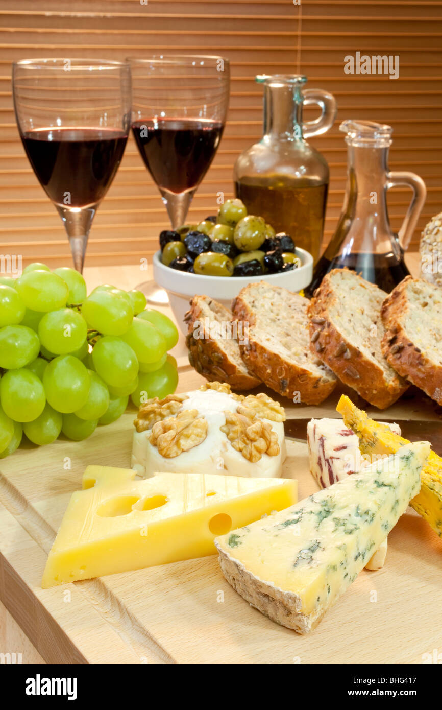 Eine Platte mit mediterranen Speisen wie Käse, Trauben, Wein, Brot, Oliven, Olivenöl und Balsamico-Essig. Stockfoto