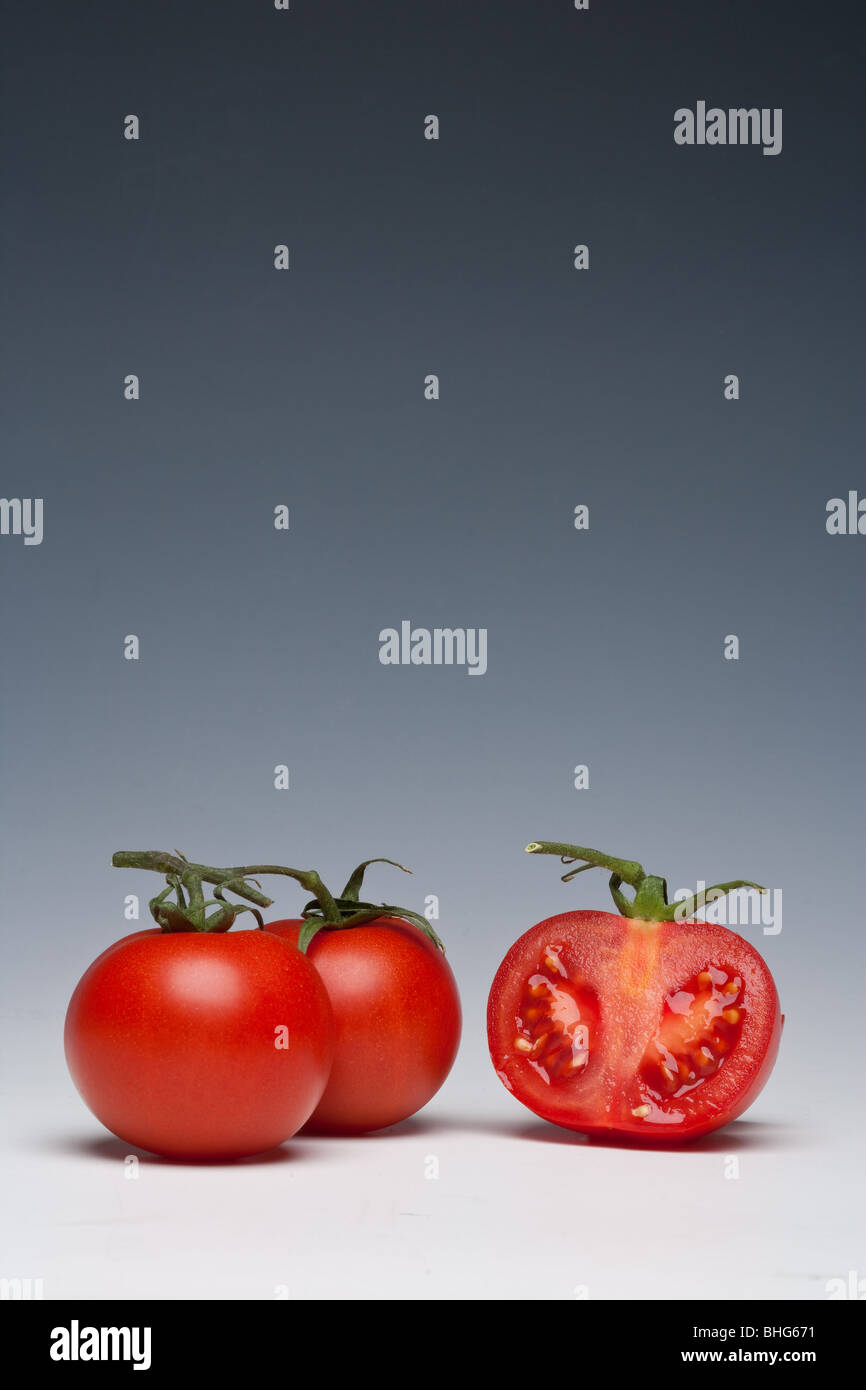 Tomaten ganze und geschnittene auf einem einfarbigen Hintergrund Stockfoto