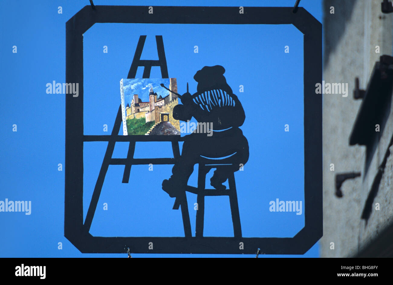 Hängekunst Galerie oder Geschäft Schild zeigt Künstler mit Easel Malerei mittelalterliche Zitadelle, Festung oder Cité de Carcassonne, Aude, Frankreich Stockfoto