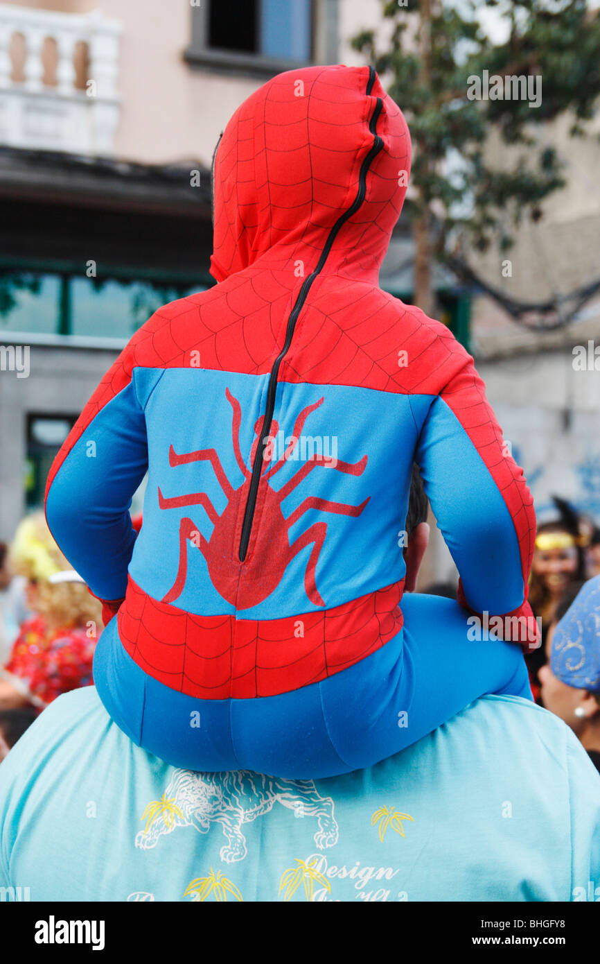 Kleiner Junge Spiderman Anzug sitzt auf Vaters Schultern an Karneval in Spanien Stockfoto
