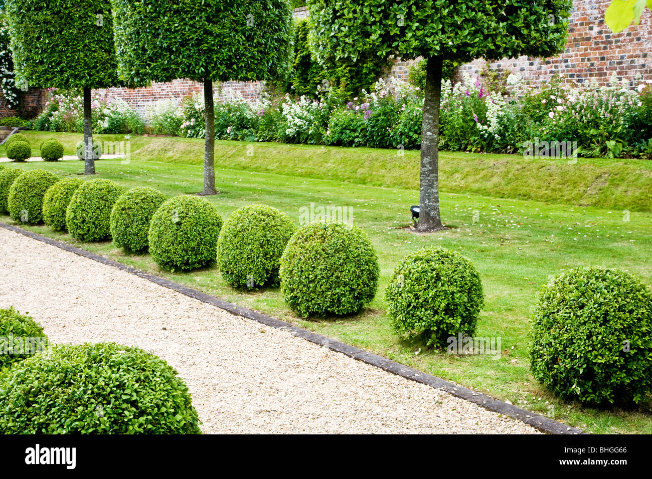 Hecke entlang einem Kiesweg in einem englischen Landhaus-Garten Stockfoto