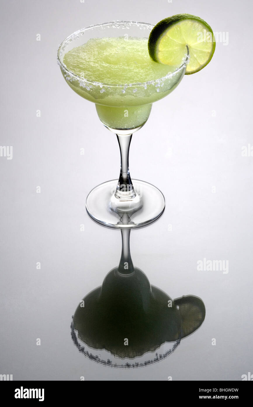Frozen Margarita Mischgetränk mit Kalk Slice Garnitur auf einfachen grauen Hintergrund mit Reflexion Stockfoto
