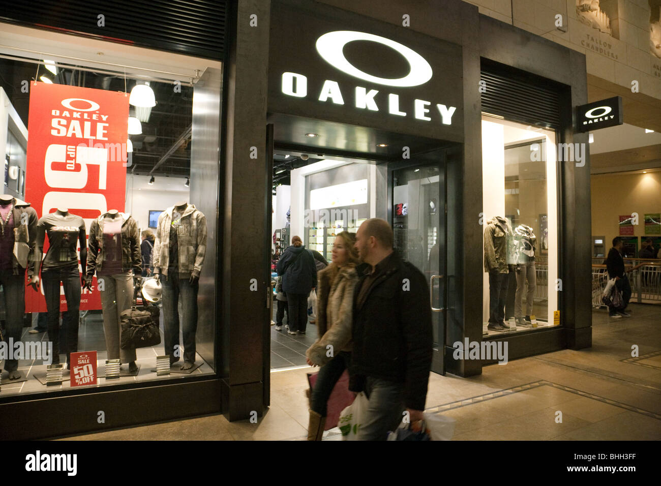 Käufer zu Fuß vor einer Oakley Bekleidungsgeschäft Bluewater Shopping-Mall, Kent, UK Stockfoto