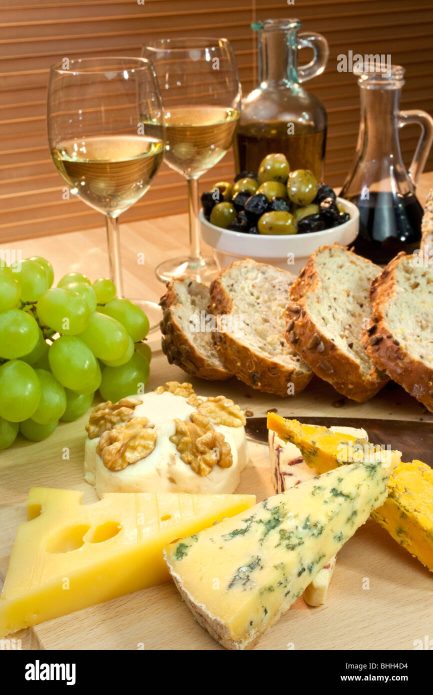 Eine Platte mit mediterranen Speisen wie Käse, Trauben, Wein, Brot, Oliven, Olivenöl und Balsamico-Essig. Stockfoto