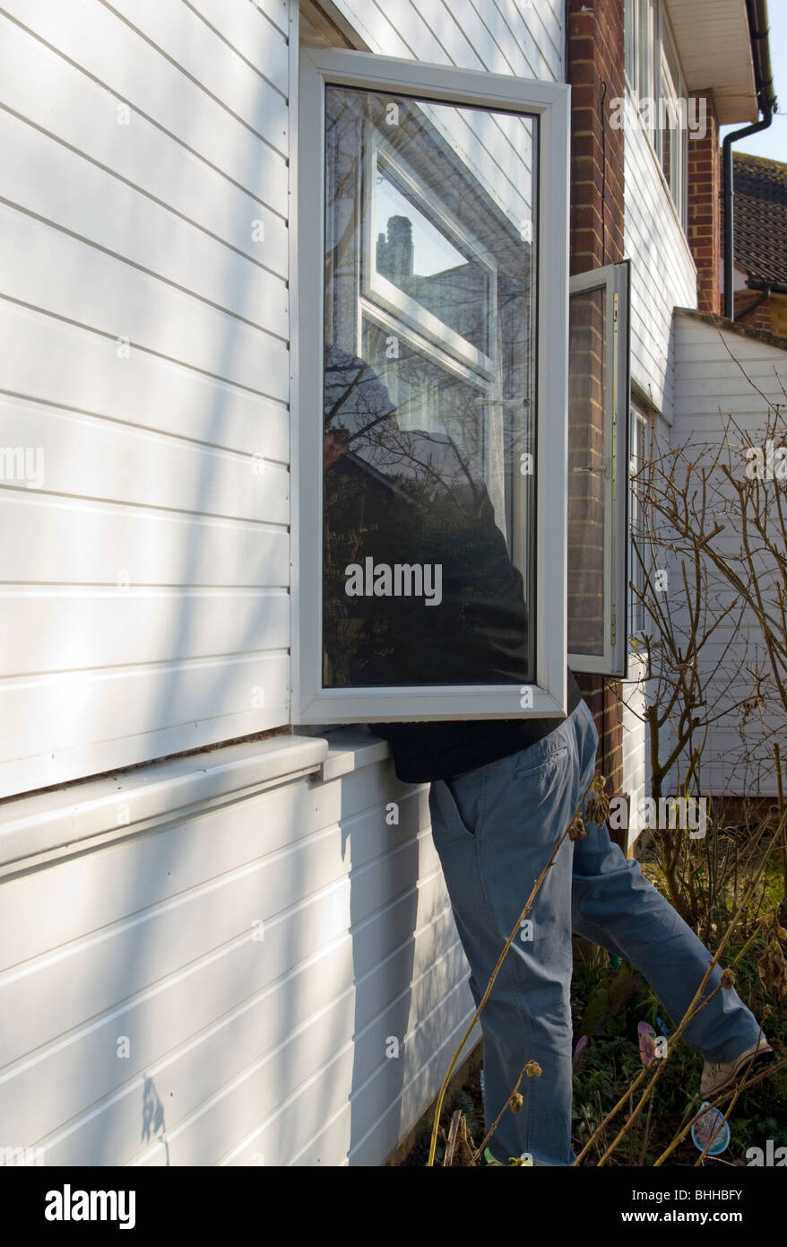 Einbrecher stützte sich durch eine offene Frontscheibe (gestellt durch Modell) Stockfoto
