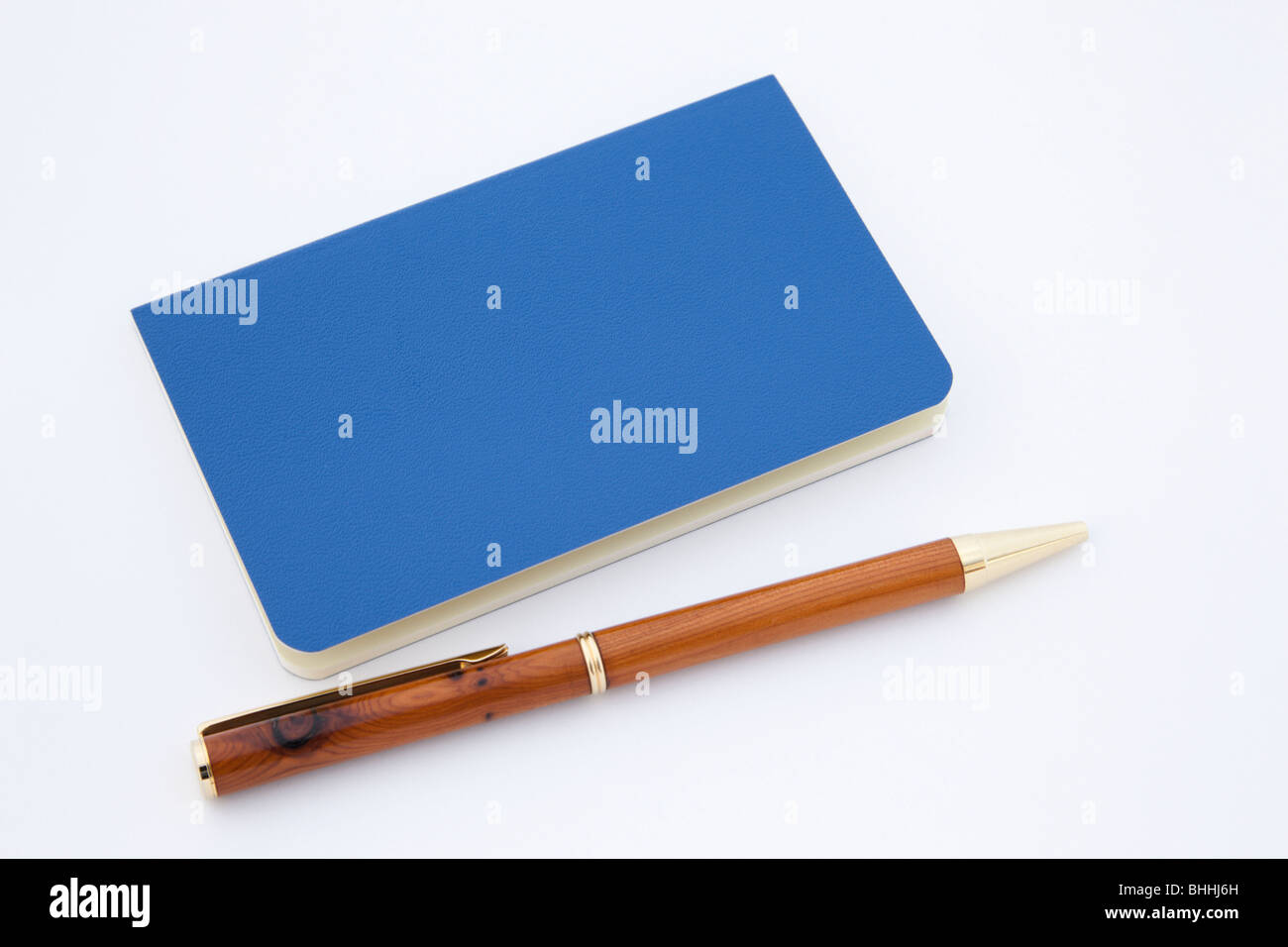 Nahaufnahme von einem blauen Moleskine-Notizbuch mit einem hölzernen Kugelschreiber auf einem weißen Hintergrund. Stockfoto