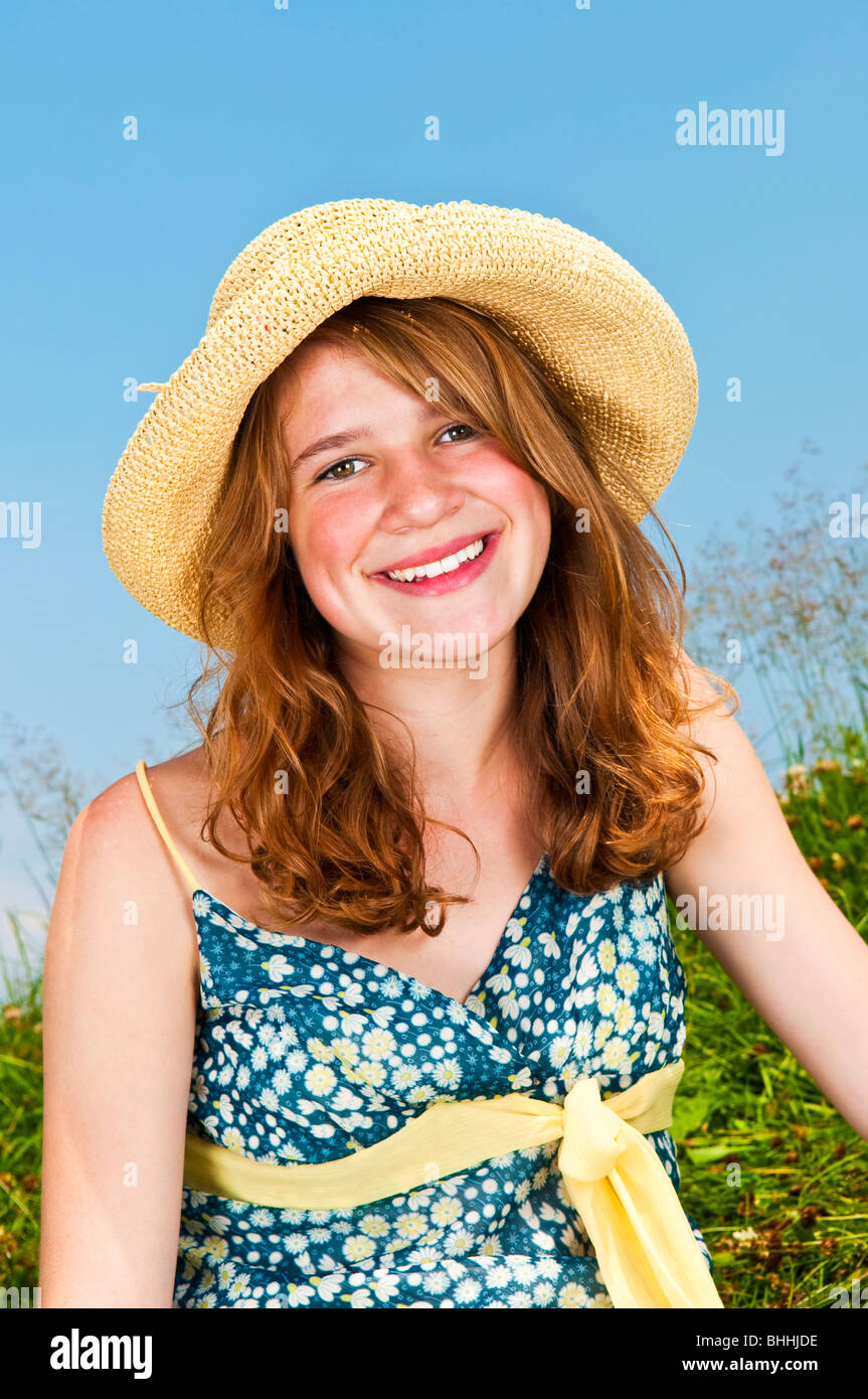 Porträt des jungen Mädchens lächelnd in Sommerwiese mit Strohhut Stockfoto