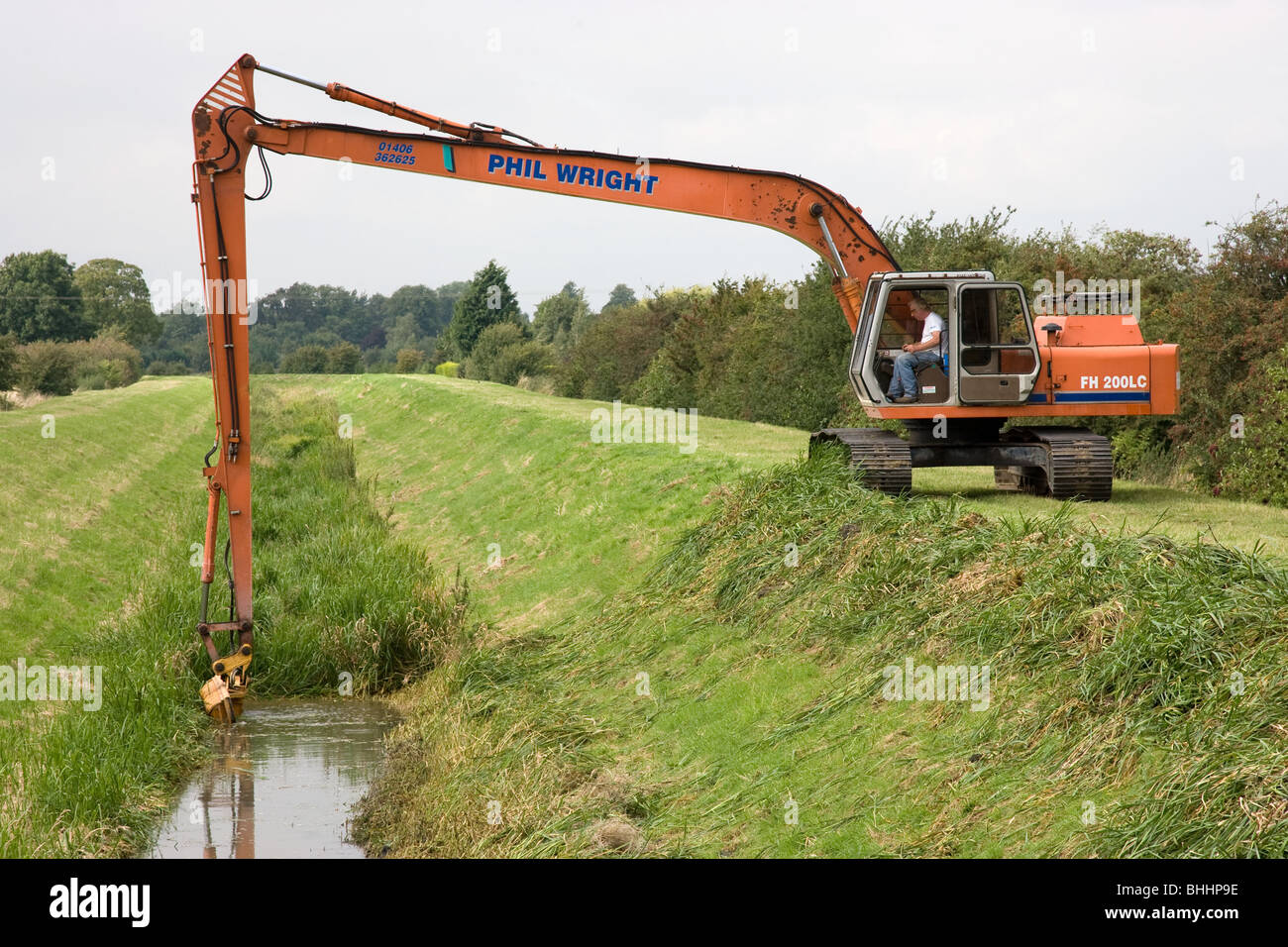 Auftragnehmer Unkraut schneiden auf einem kleinen Fenland Abfluss in Lincolnshire Stockfoto