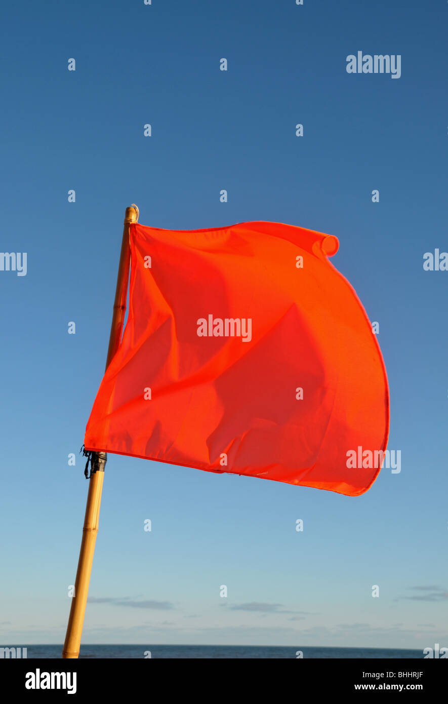 Eine rote Fahne am Strand im Wind wehen. Stockfoto