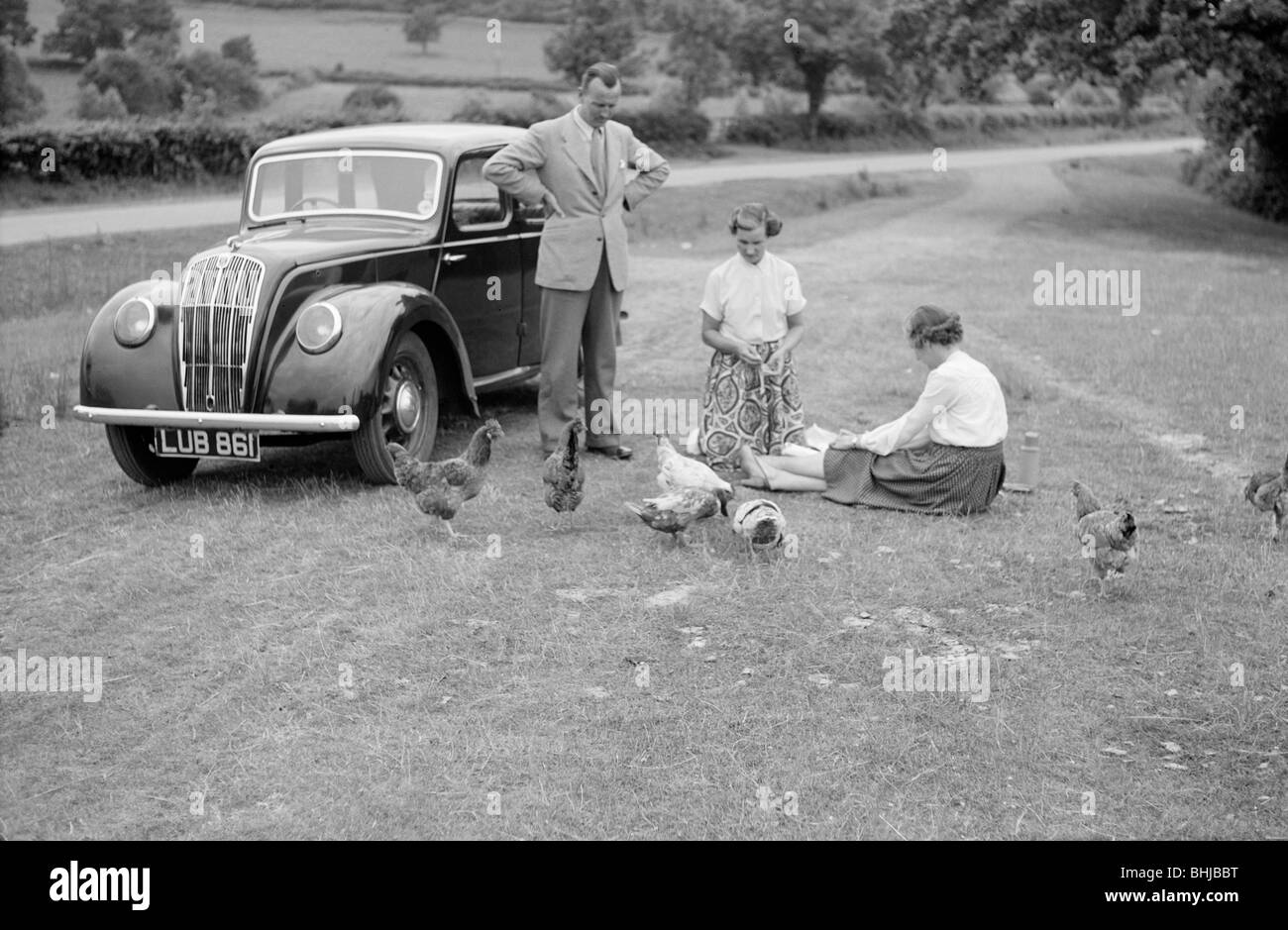 Eine Familiengruppe füttere Hühner neben ihrem Auto, c1945-c1965. Künstler: SW Rawlings Stockfoto