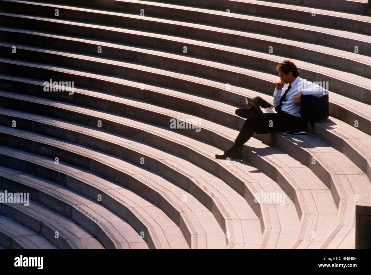Geschäftsmann mit Handy und Aktenkoffer ruht auf die Innenstadt von Civic Center Schritte in Los Angeles, Wall Street Journal lesen Stockfoto