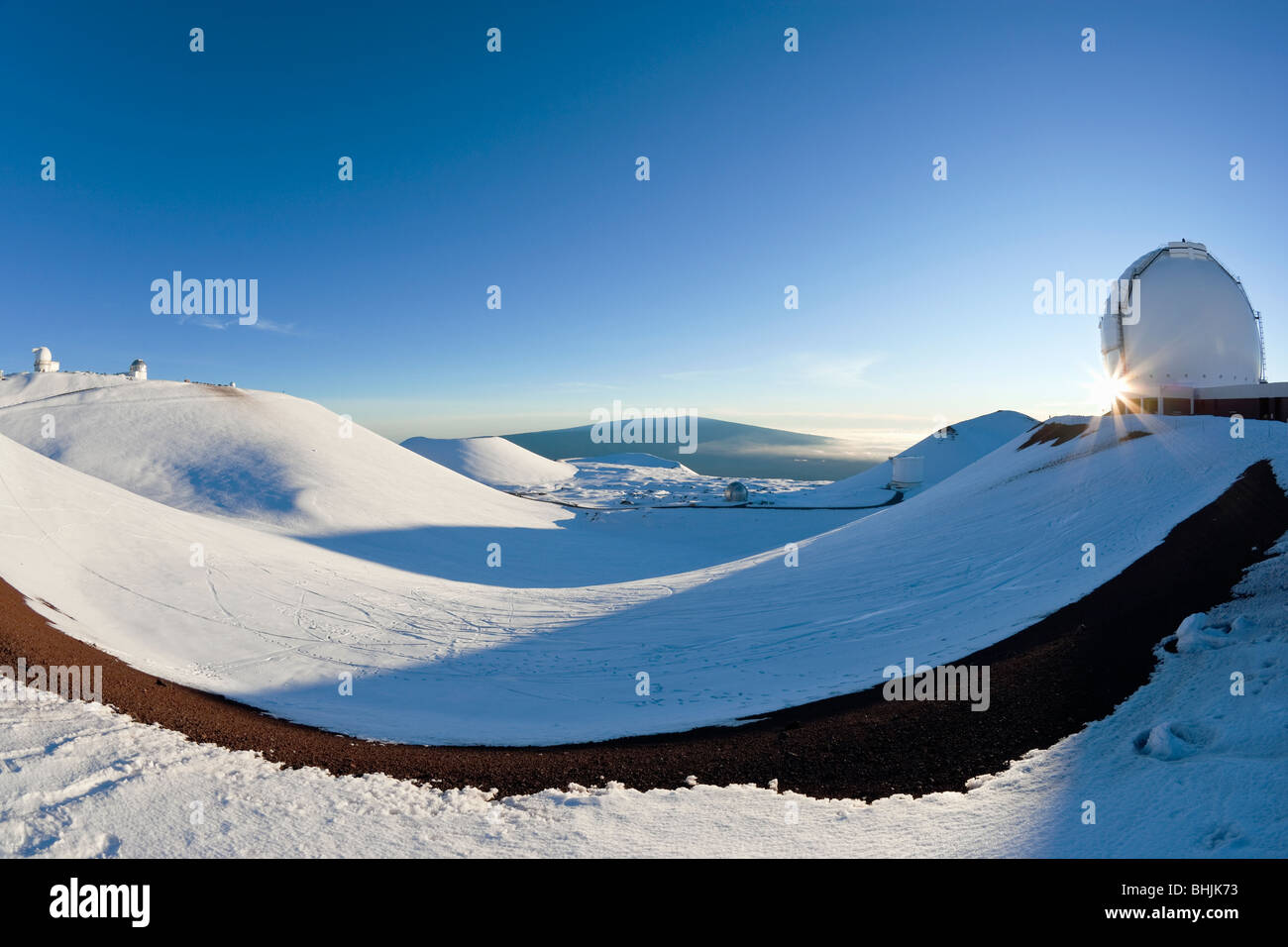 Blick vom Mauna Kea auf Mauna Loa als Sonne platzt hinter Keck Observatorium an einem Wintertag in Hawaii. Stockfoto