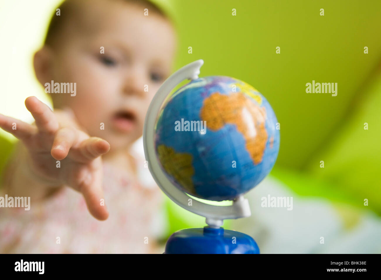 Baby Mädchen greifen nach Spielzeug Globus Stockfoto