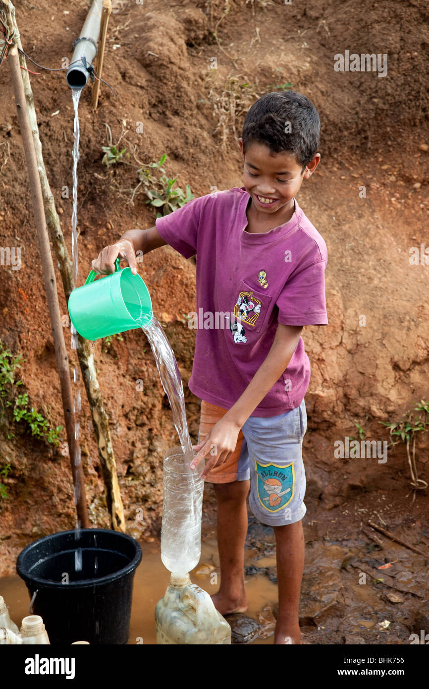 Kleiner Junge den Kanister mit Wasser füllen Stockfoto
