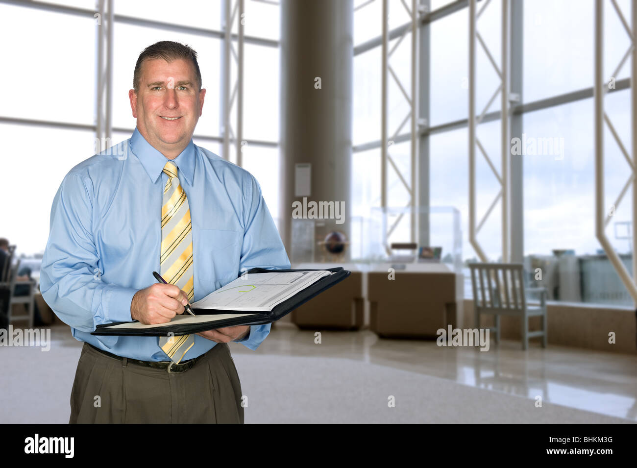 Ein reifer Geschäftsmann Notizen in eine große lobby Stockfoto