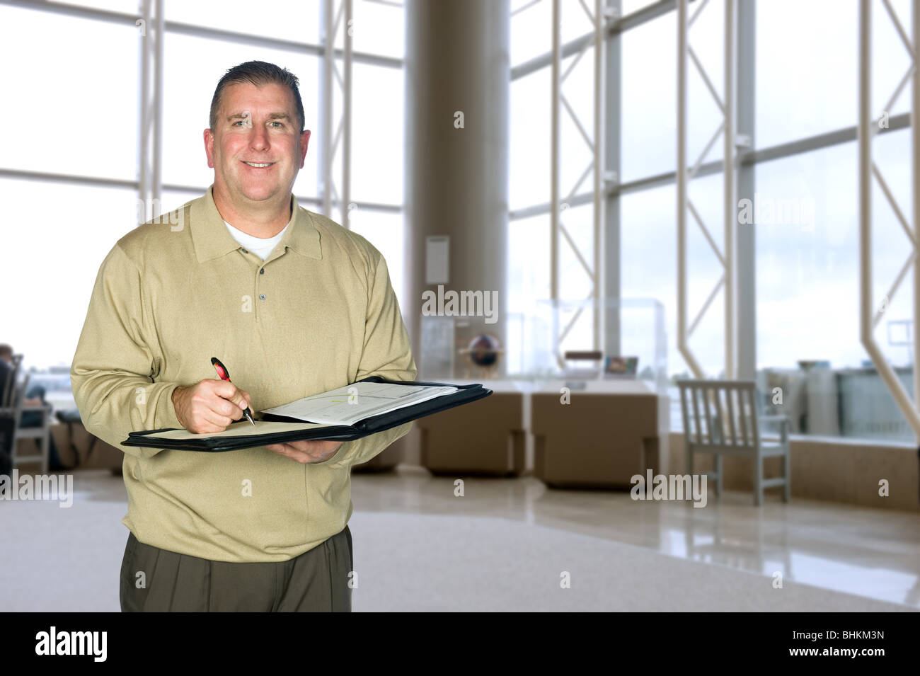 Ein reifer Geschäftsmann tragen legere Kleidung, die Notizen in eine große lobby Stockfoto