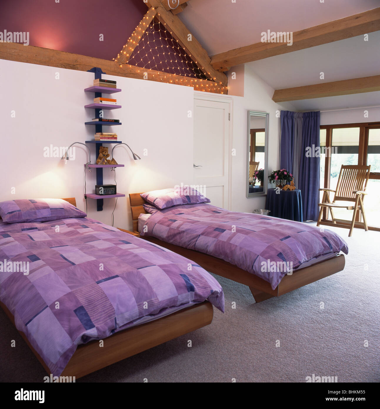 Lila gemusterten Bettdecken auf Twin Betten in modernen Mansarde mit eingelassene Deckenbeleuchtung Stockfoto