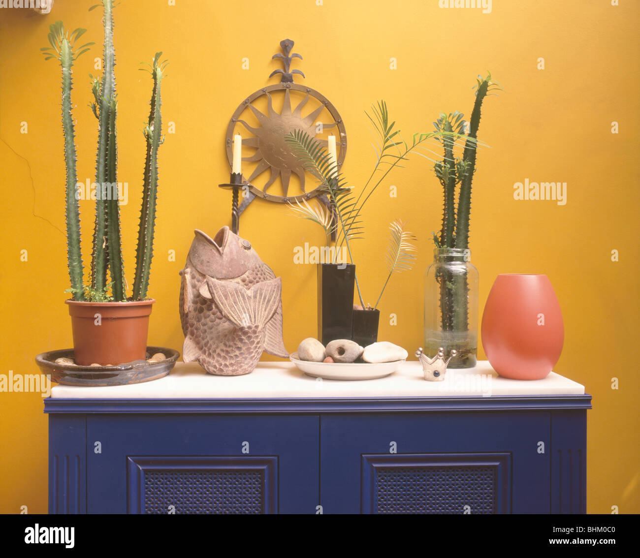 Nahaufnahme von Kakteen im Topf auf blau Sideboard mit großen Fischen Ornament im hellen gelben Esszimmer Stockfoto