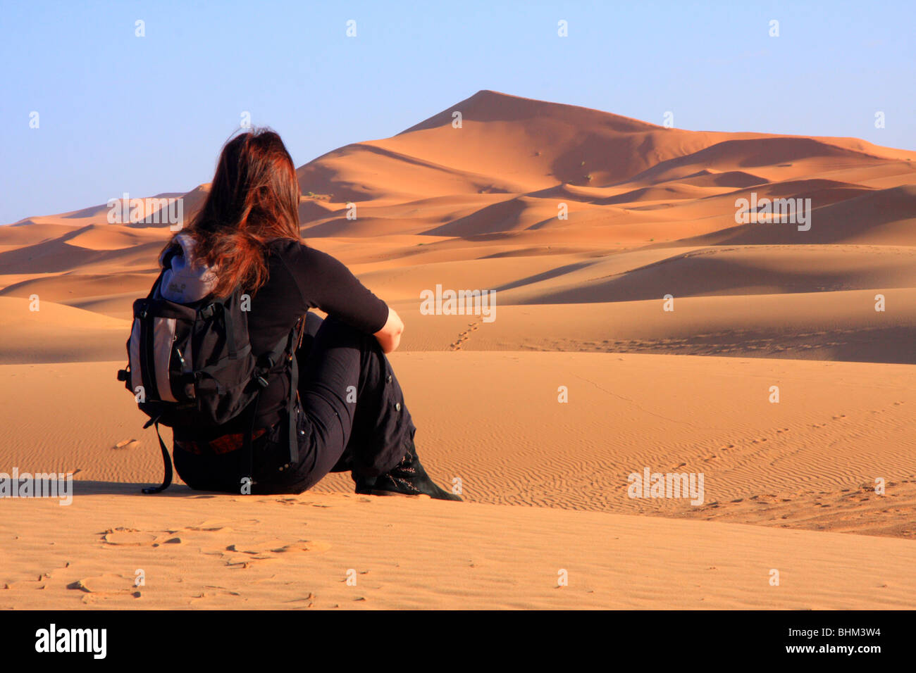 Einsame weibliche Touristen blickt auf den Erg Chebbi Snad Dünen der Sahara-Wüste in der Nähe von Merzouga, Marokko Stockfoto