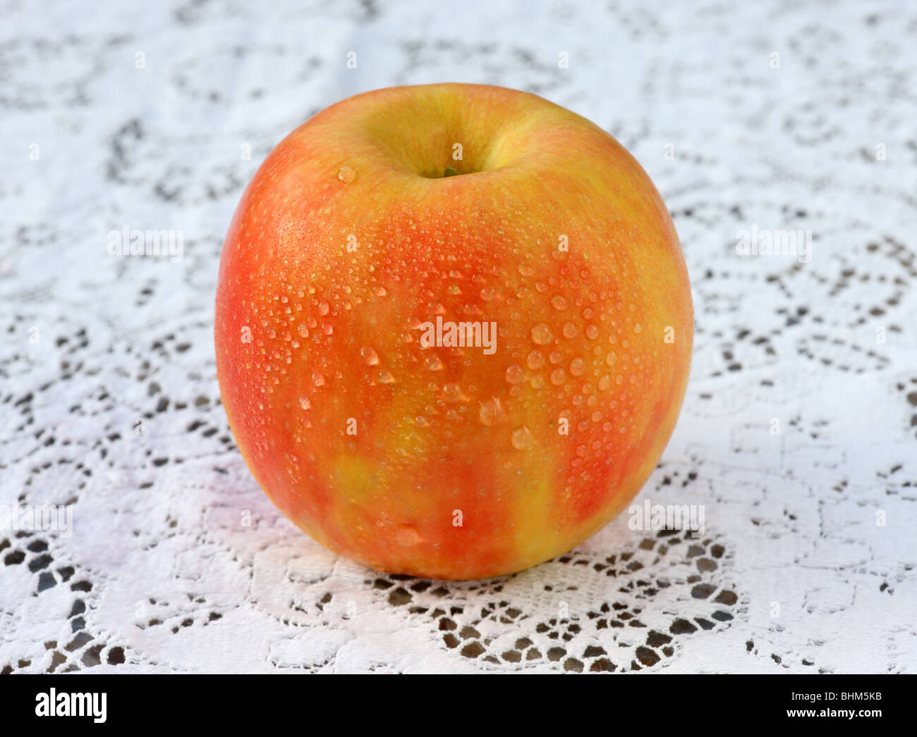 Frisch, reifer, Pink Lady Apfel mit Wasser tropft auf Spitze Tischdecke. Stockfoto