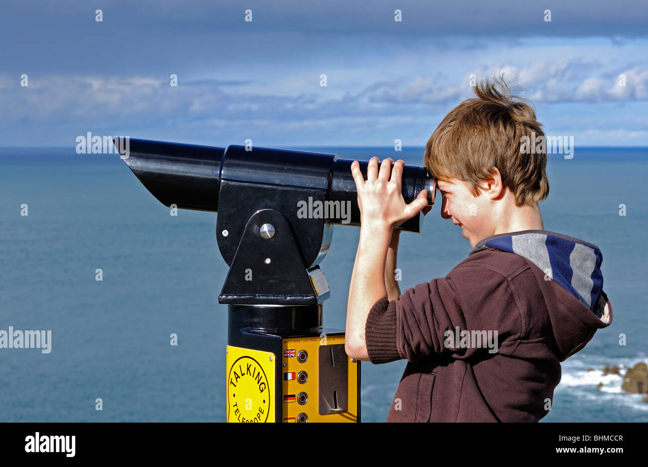 ein kleiner Junge, der Blick durch ein Teleskop bei Lands End in Cornwall, Großbritannien Stockfoto