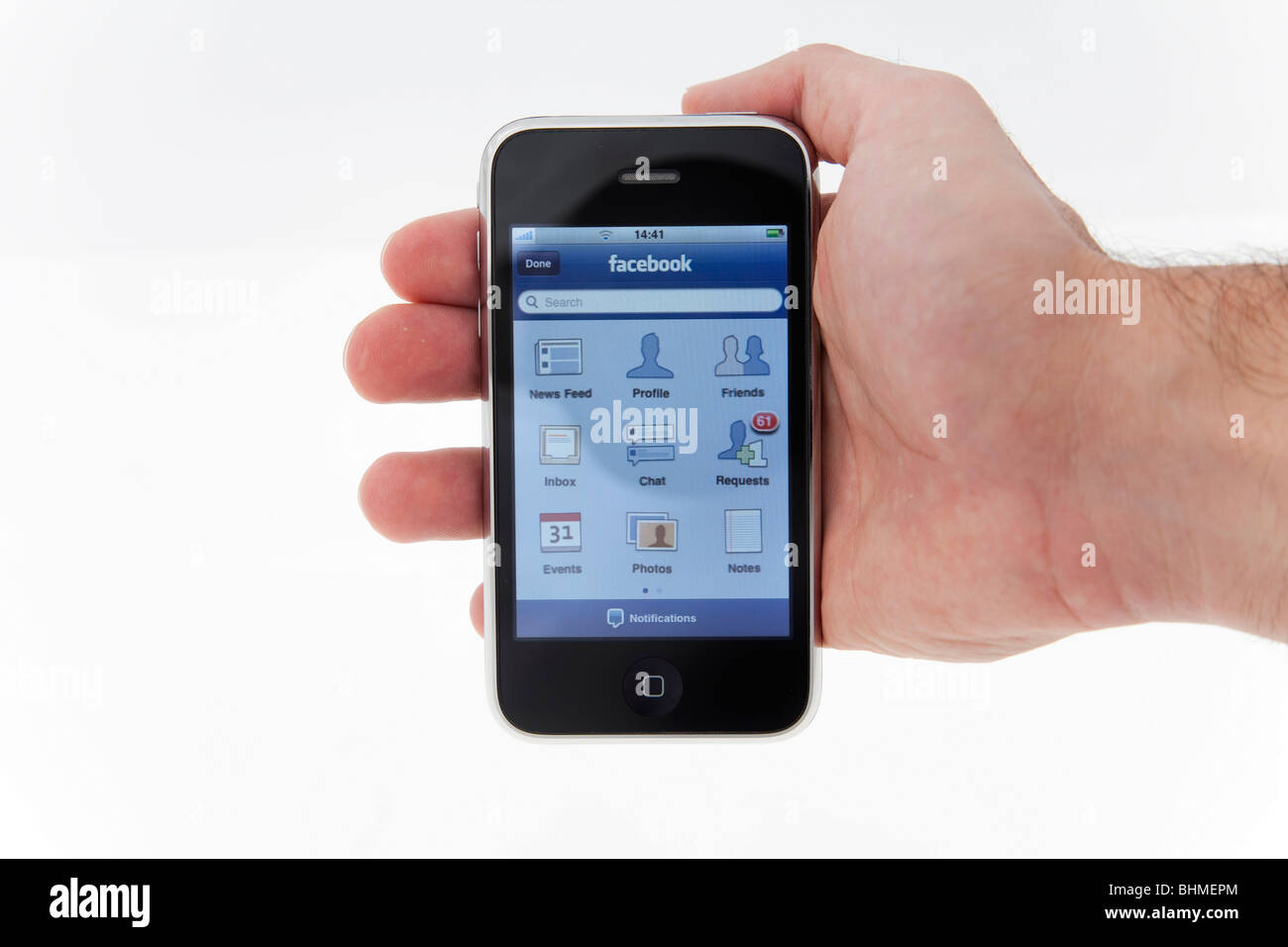 Hand hält iPhone Anzeige Facebook-Startseite auf weißem Hintergrund Stockfoto